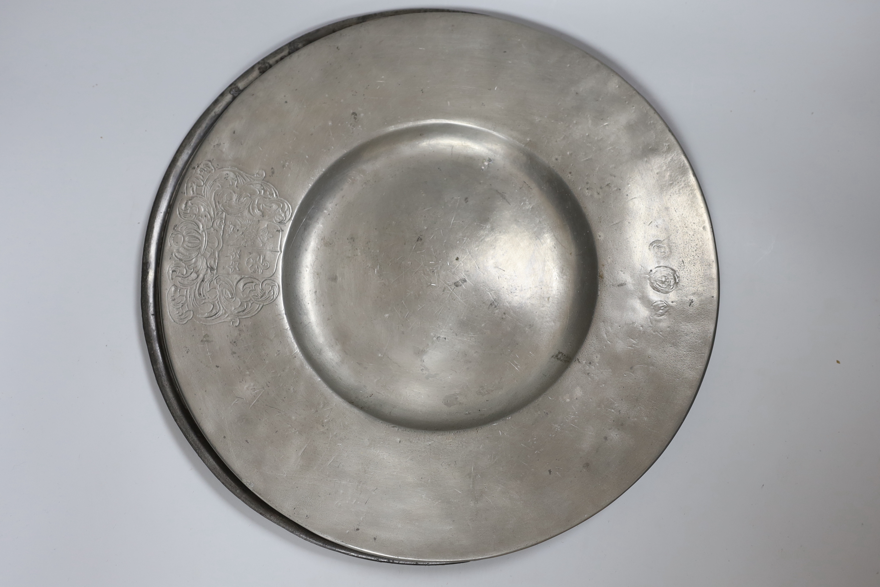 Two pewter chargers one crested, eight plates and a jug, 18th century and later, largest charger 38cms diameter